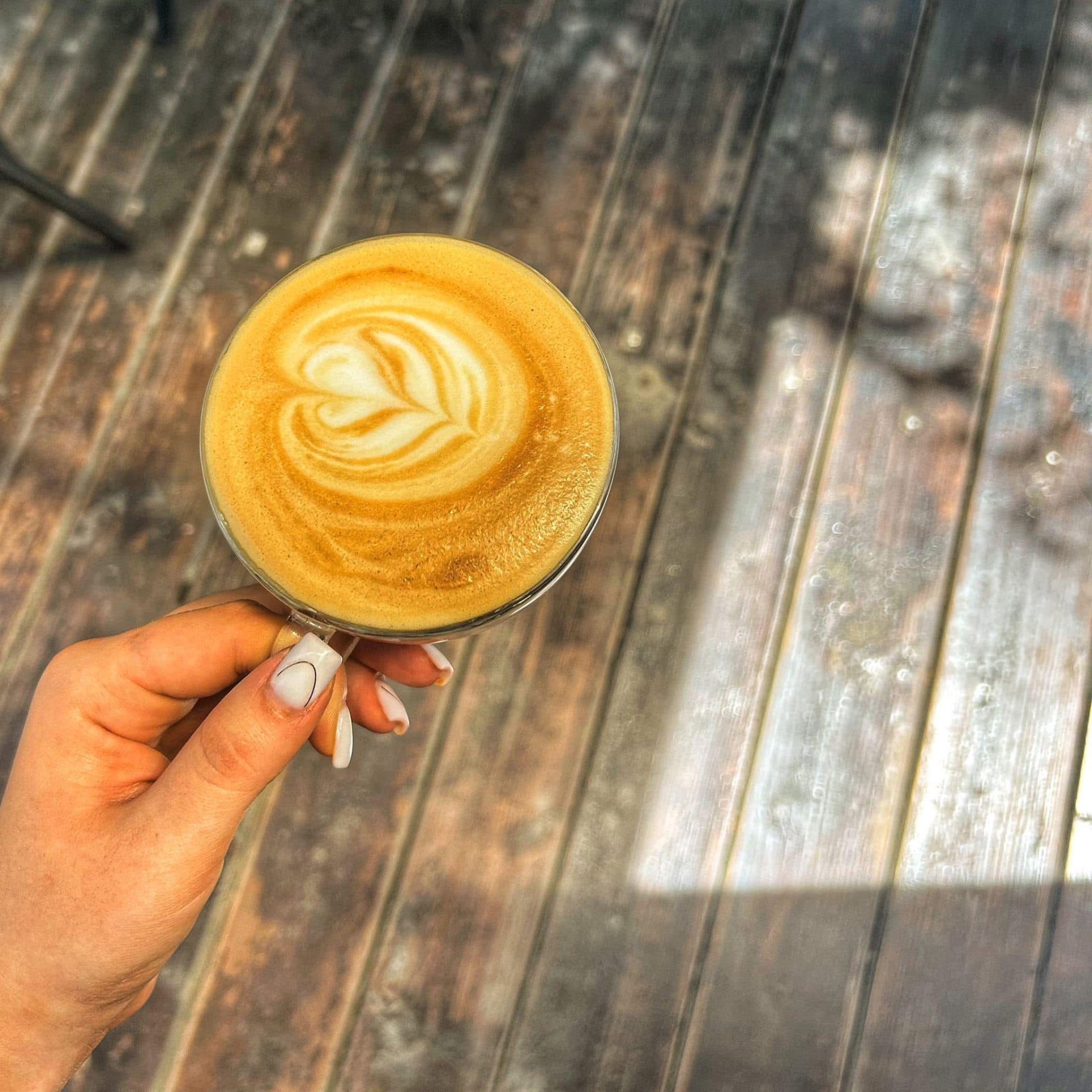 Două cești de cafea pe o masă de lemn la Mira Coffee